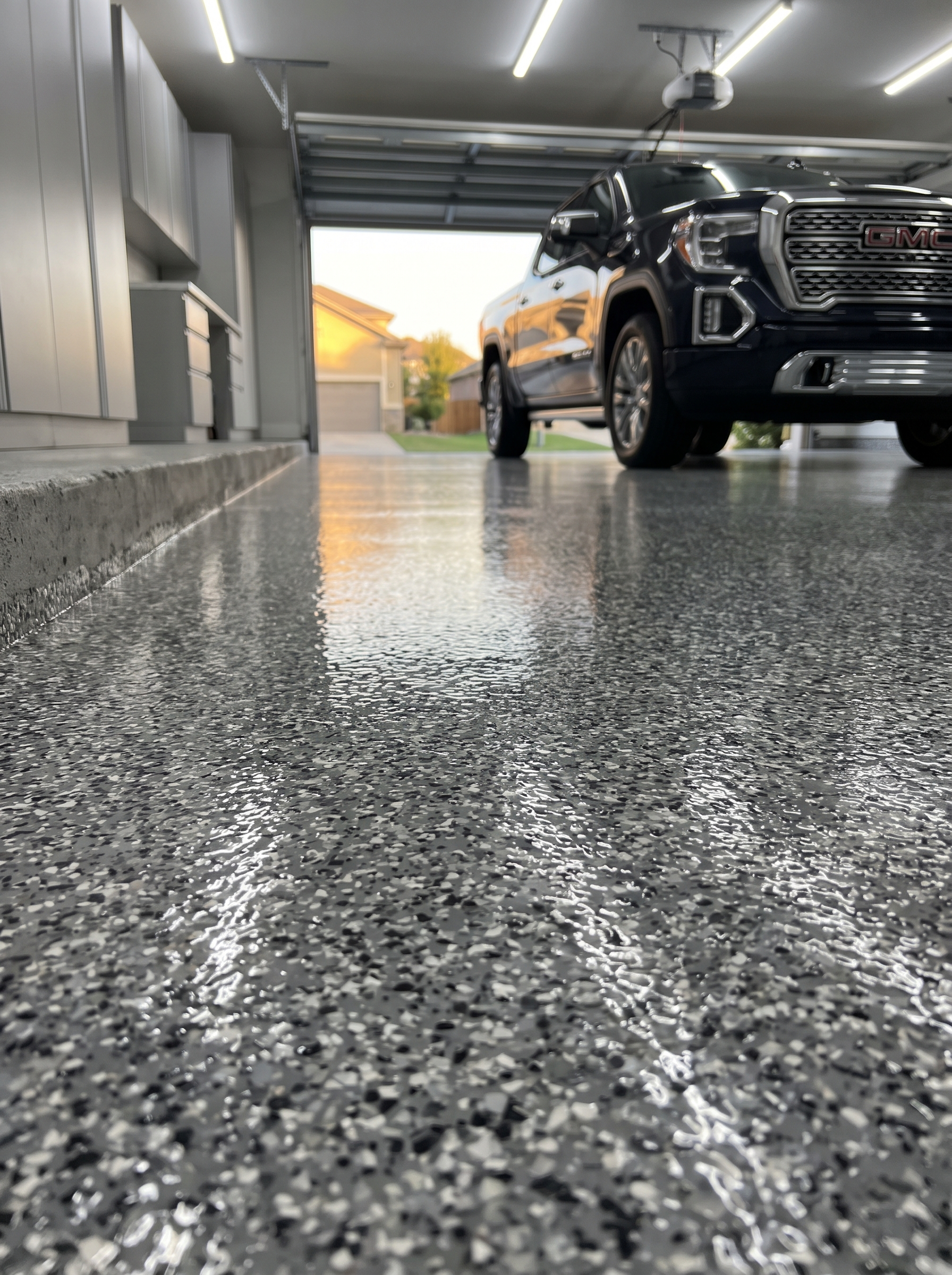 Low angle view of a finished gray flake garage floor, the mid-tone blend that hides dirt and tire marks best, installed in Granbury, North Texas