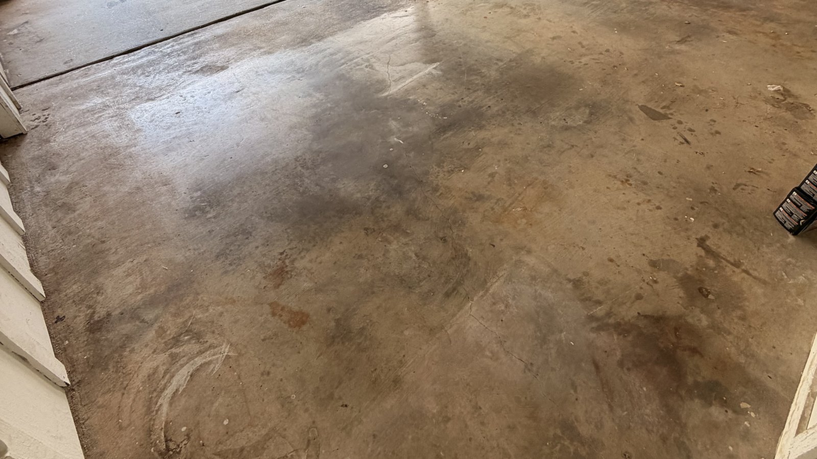A stained bare concrete garage floor in North Texas, the kind of slab people ask about sealing