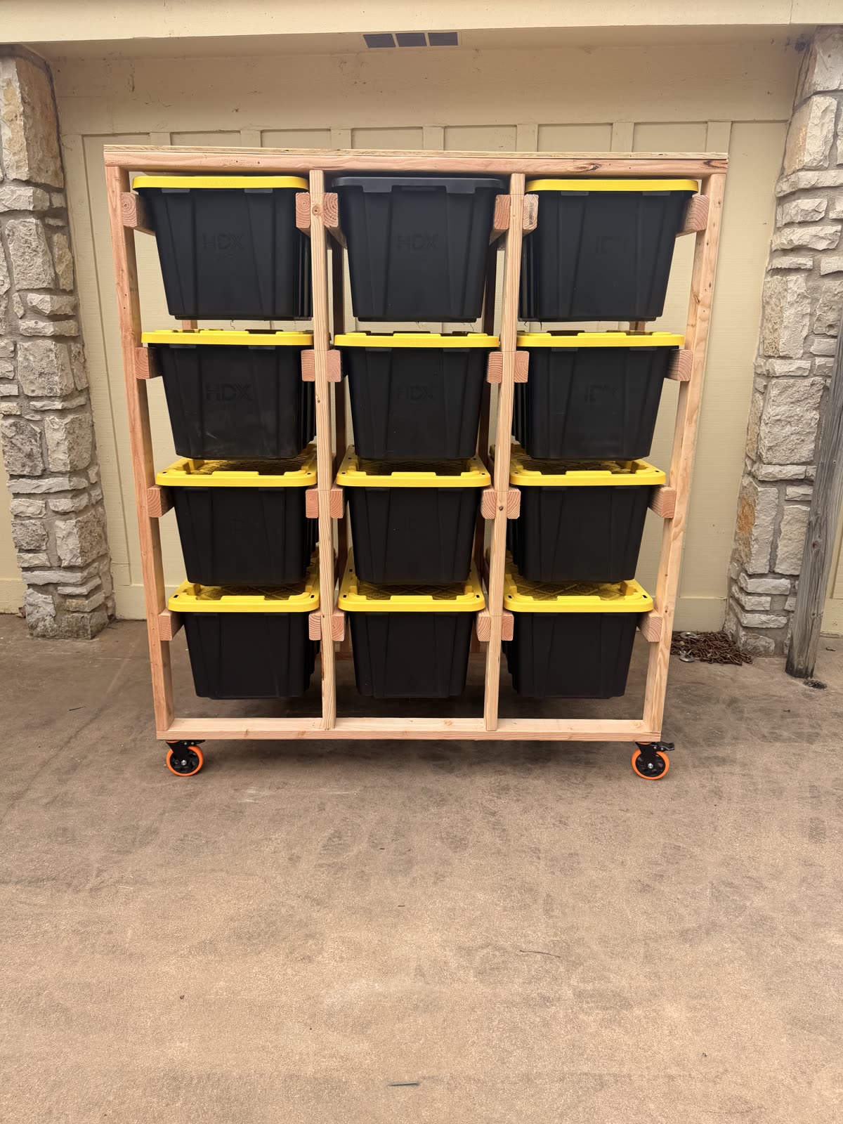 A 12-tote rolling storage rack built by Happy Slab Coatings, loaded with black and yellow HDX 27-gallon totes